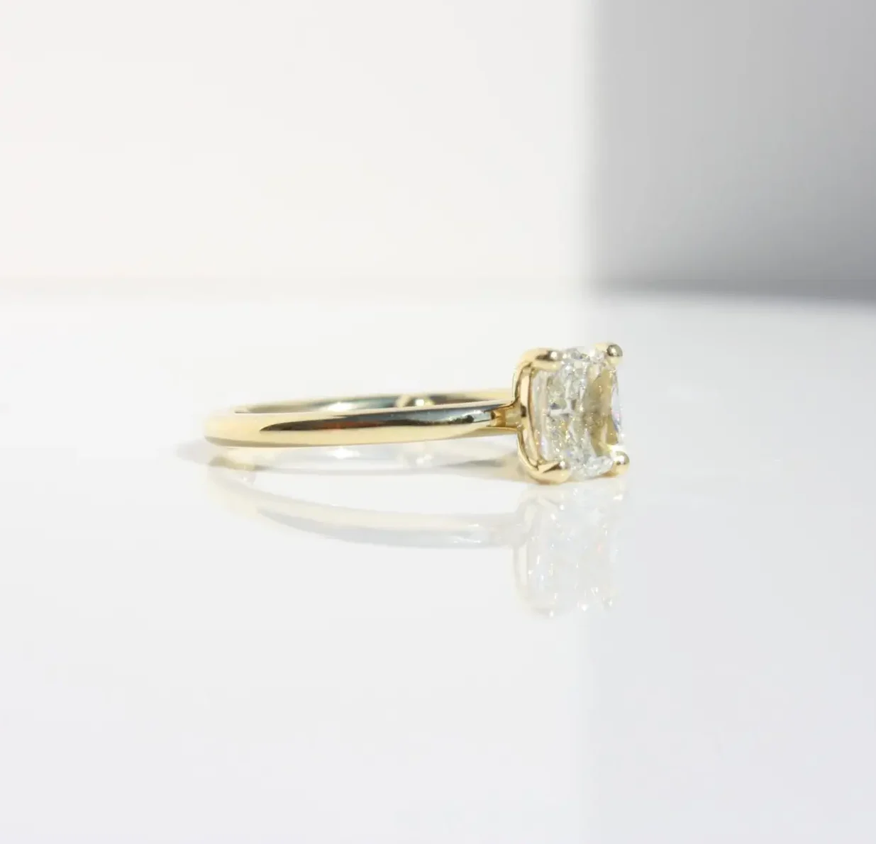 Yellow gold engagement ring with cushion cut diamond solitaire on minimalist band