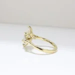 A gold ring featuring a marquise-cut diamond at the center, flanked by two smaller pear-shaped diamonds on either side, displayed against a clean white background.