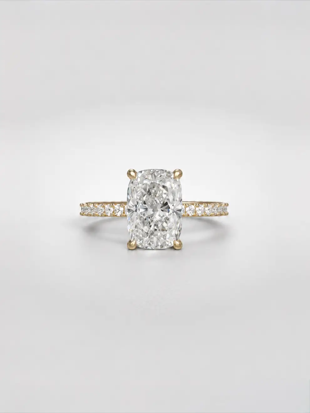 Elongated cushion-cut diamond ring with a hidden halo and a sparkling pavé melee diamond band on a gold cathedral setting.