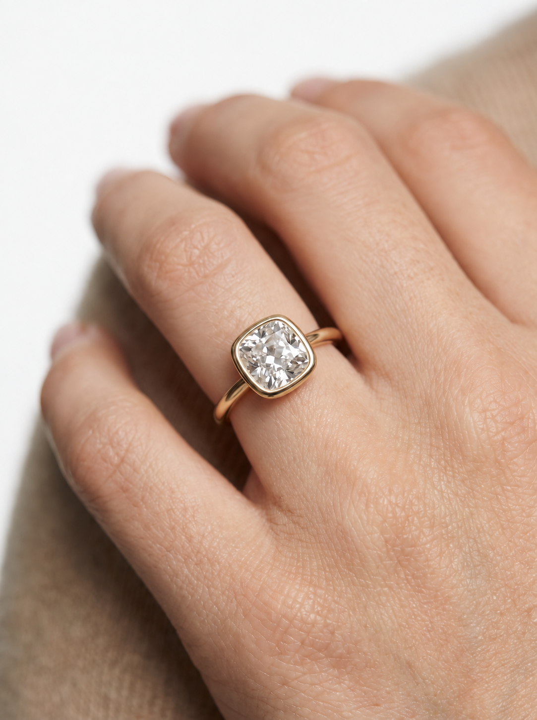Bezel-set cushion diamond ring in a sleek gold tube mounting on an elevated cathedral setting.