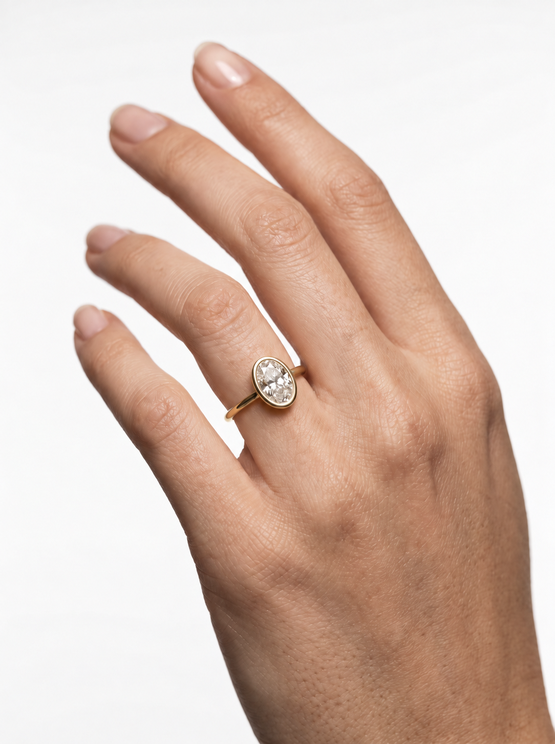 Bezel-set oval lab-grown diamond ring in a sleek gold tube mounting on an elevated cathedral setting.