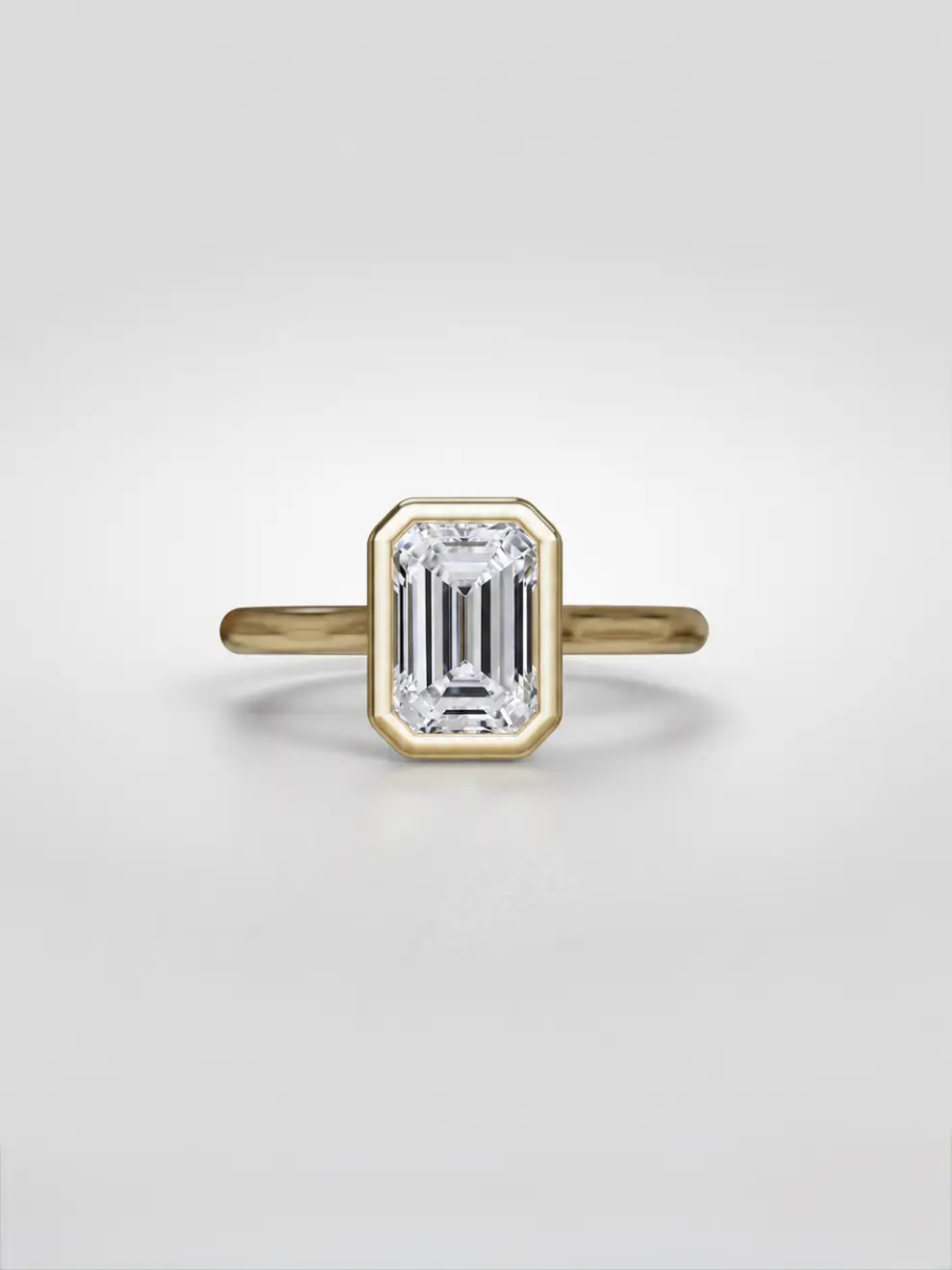 Bezel-set emerald-cut diamond ring in a sleek gold tube mounting on an elevated cathedral setting.