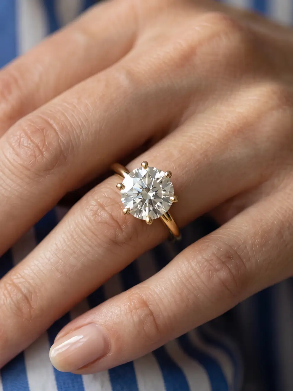 Round brilliant-cut lab-grown diamond solitaire ring with six sleek claw prongs on a gold band.