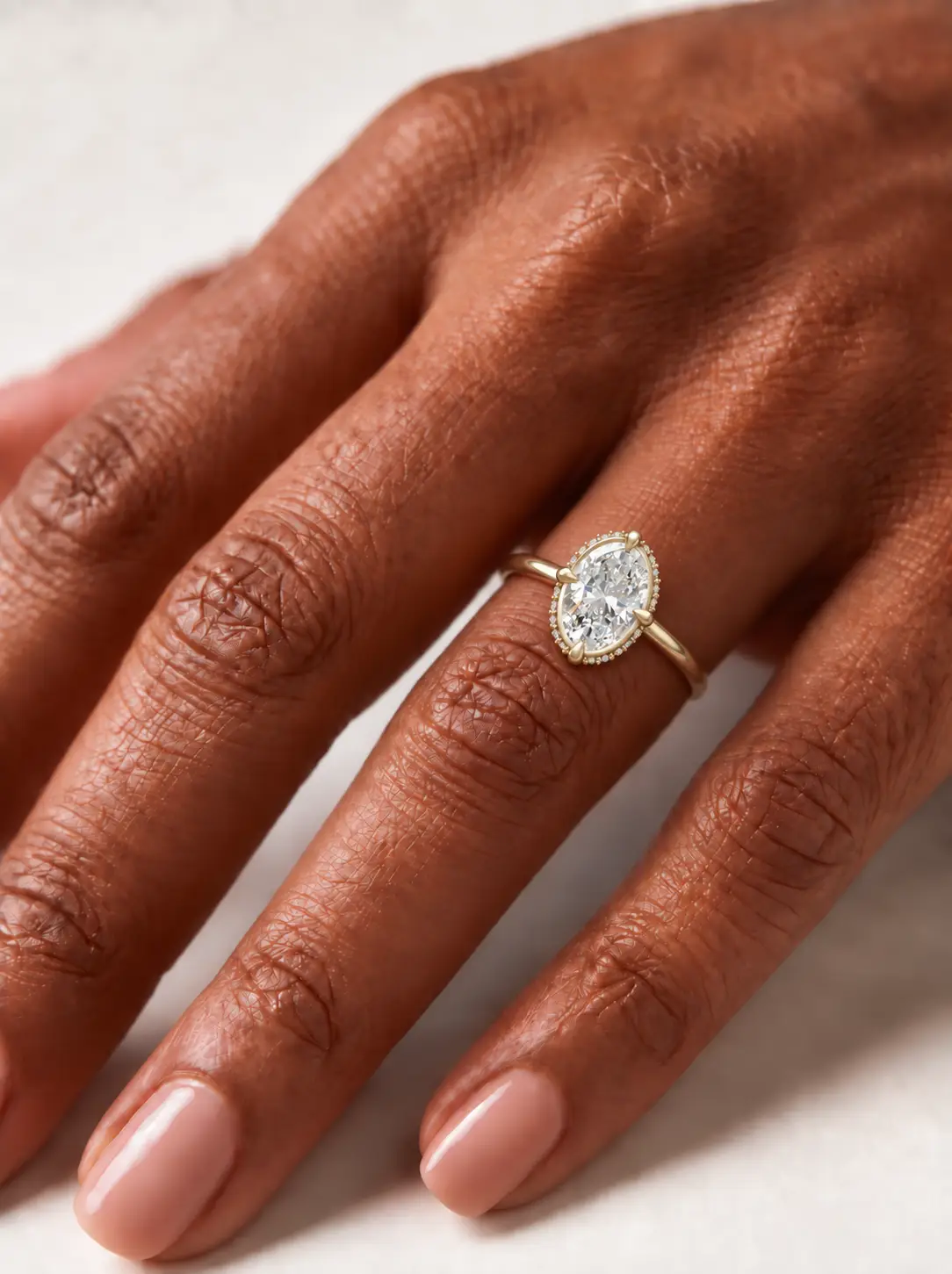 Oval diamond compass halo ring with an offset melee diamond border on a slender gold band.