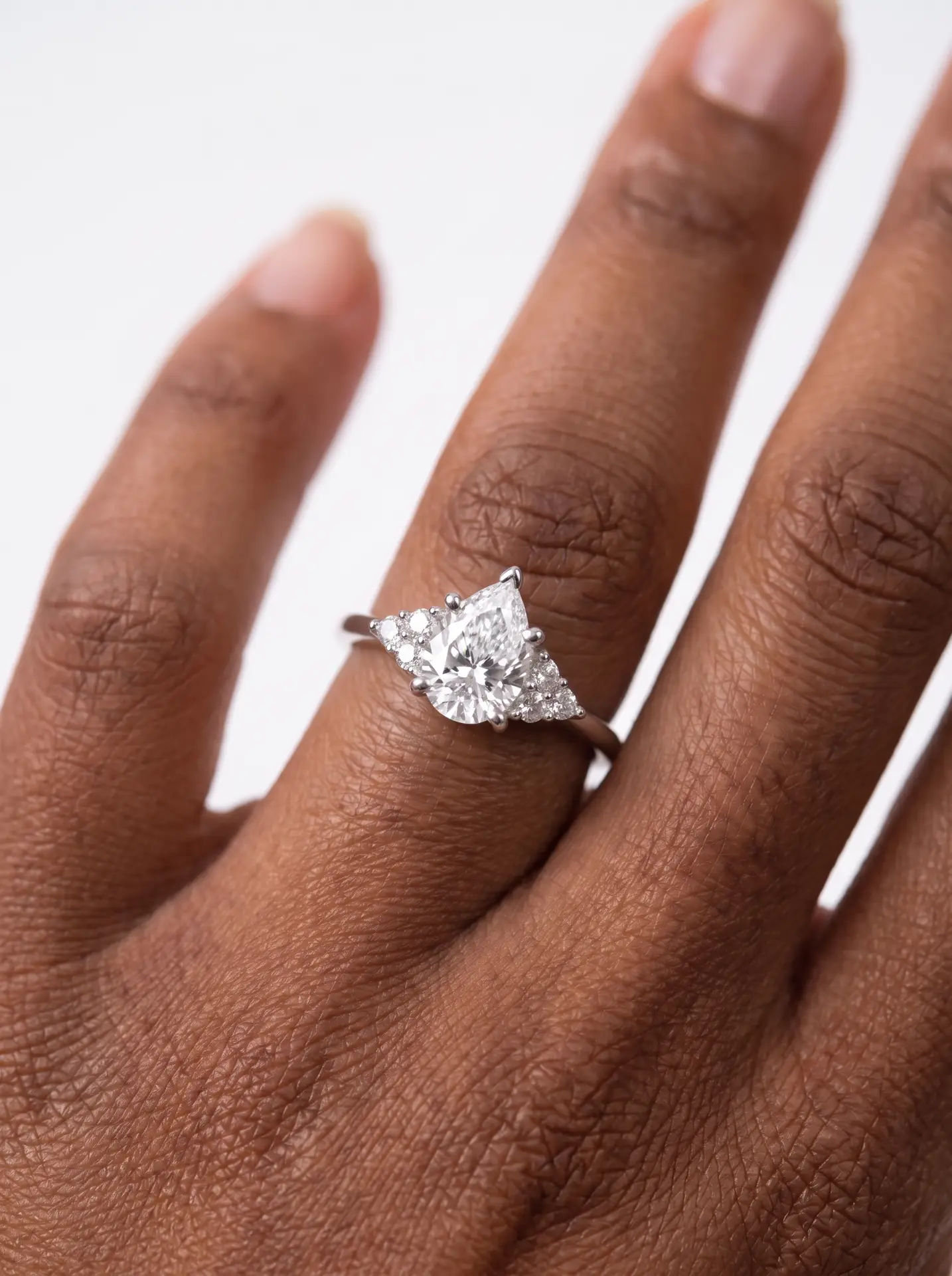 Cluster diamond engagement ring with a oval center stone flanked by brilliant accent diamonds on a gold cathedral setting.