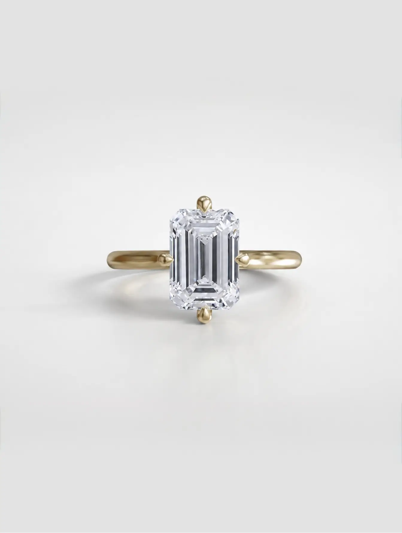 Emerald-cut diamond solitaire ring with NSEW compass claw prongs on a gold cathedral setting