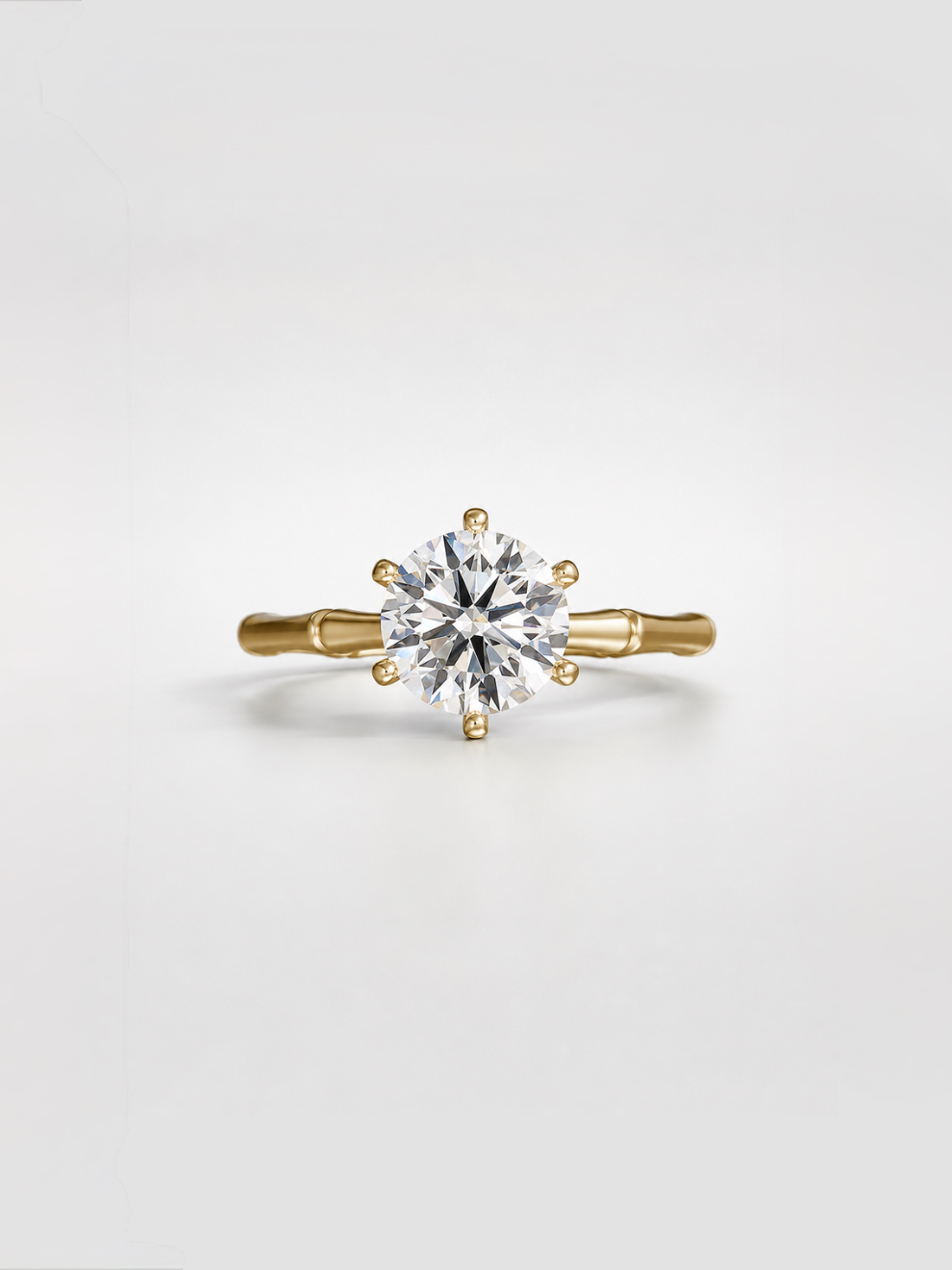 Round diamond solitaire ring with an open gallery and gold bamboo band.