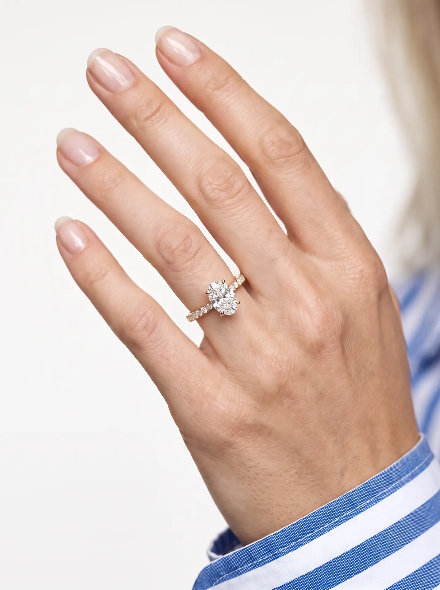 Oval diamond solitaire ring with a gold pavé band.