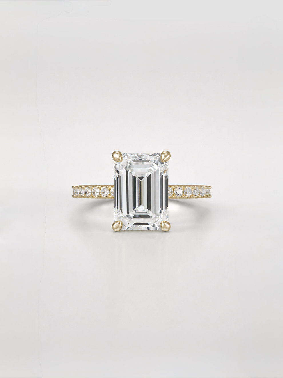 Emerald-cut diamond solitaire ring with a gold pavé band.