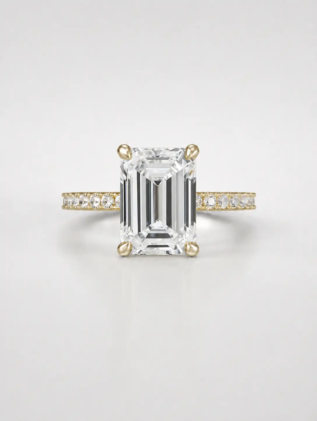 Emerald-cut diamond solitaire ring with a gold pavé band.