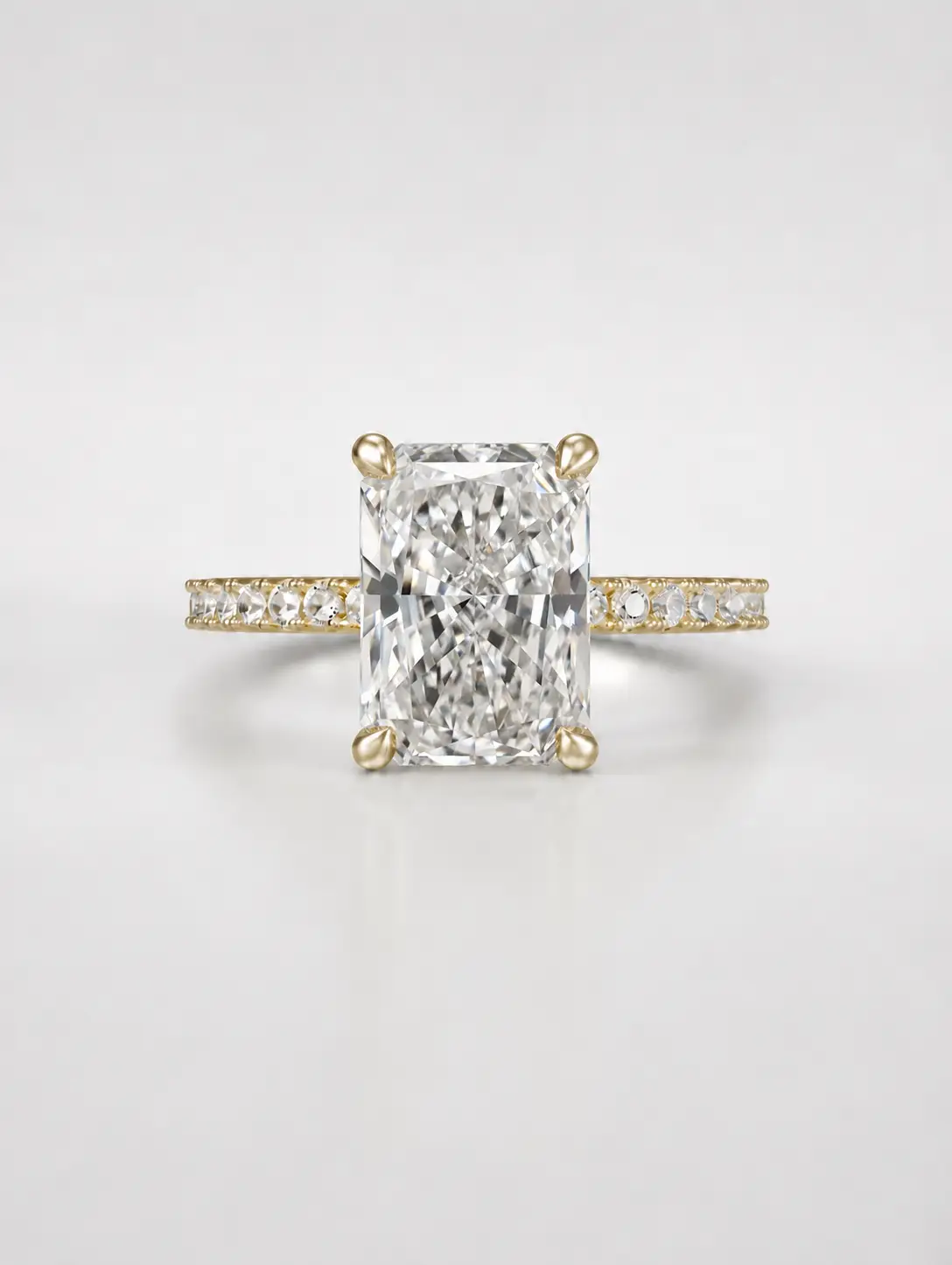 Radiant-cut diamond solitaire ring with a gold pavé band.