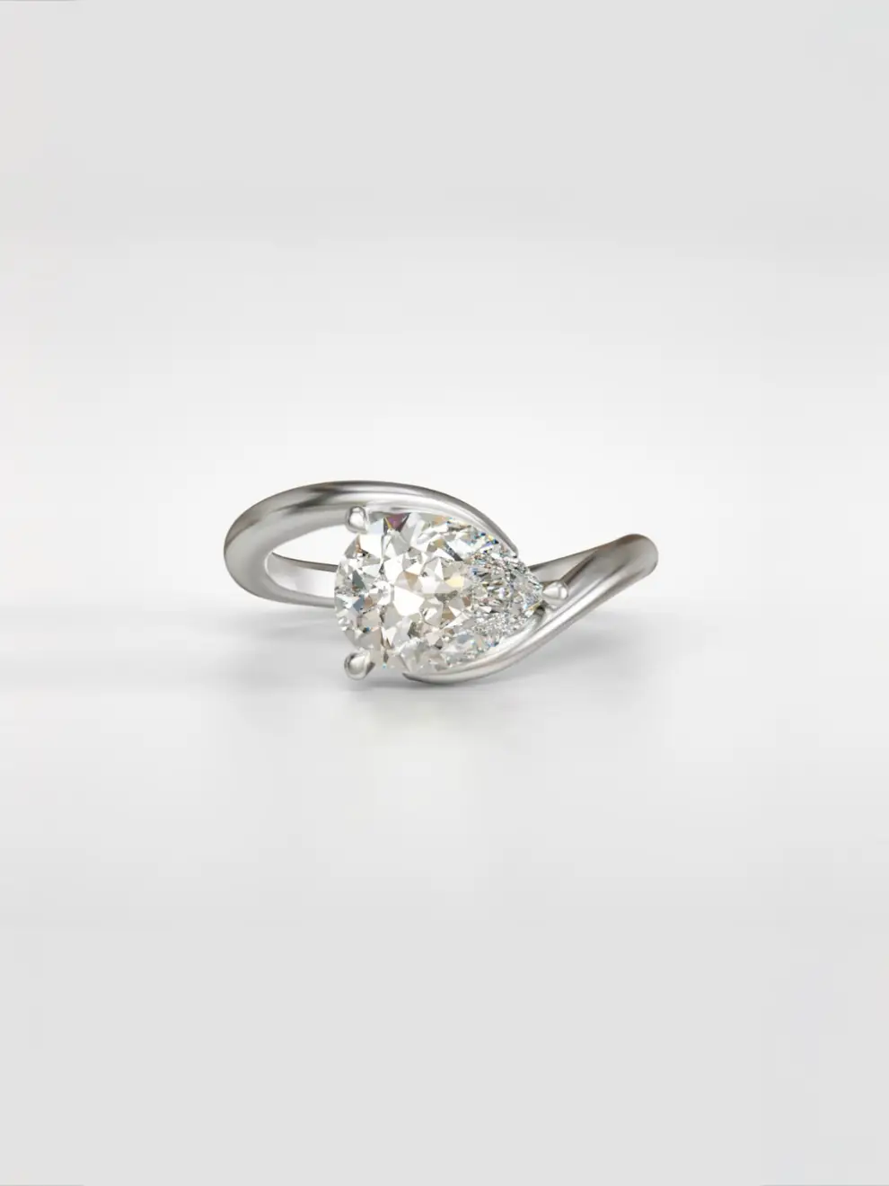 East-west pear diamond solitaire ring nestled in a gold bypass band.