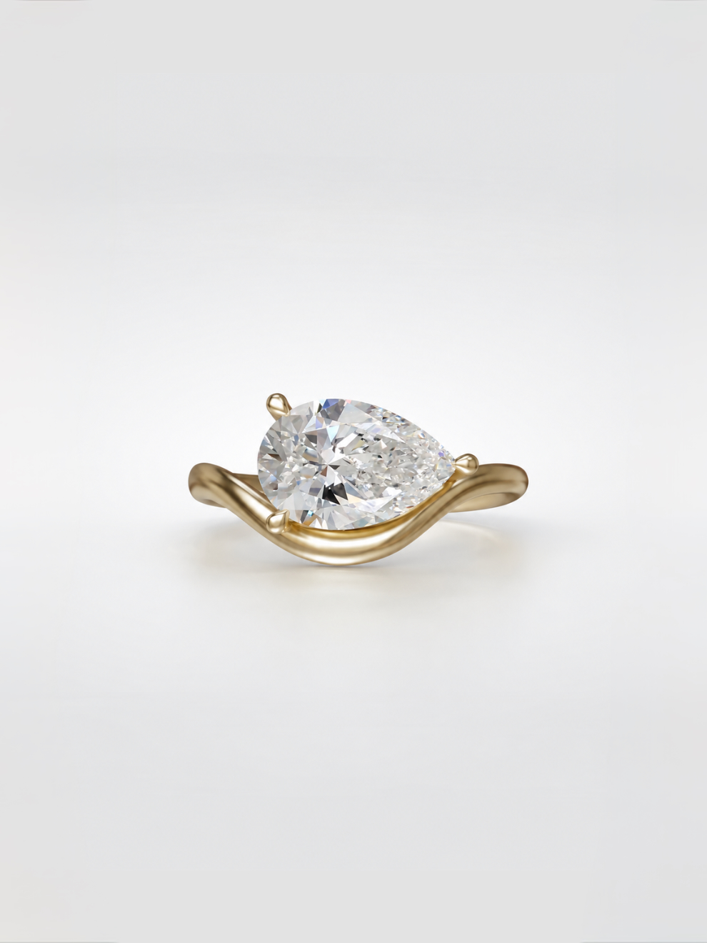 East-west pear diamond solitaire ring with a graduated-contour gold band.
