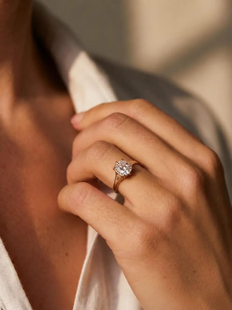 Women wearing a oval cut diamond solitaire engagement ring on a tapered yellow gold band with a collet setting.