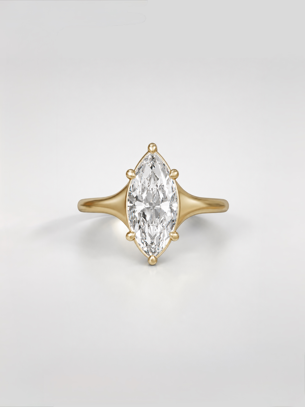 Marquise cut diamond solitaire engagement ring on a tapered yellow gold band with a collet setting.
