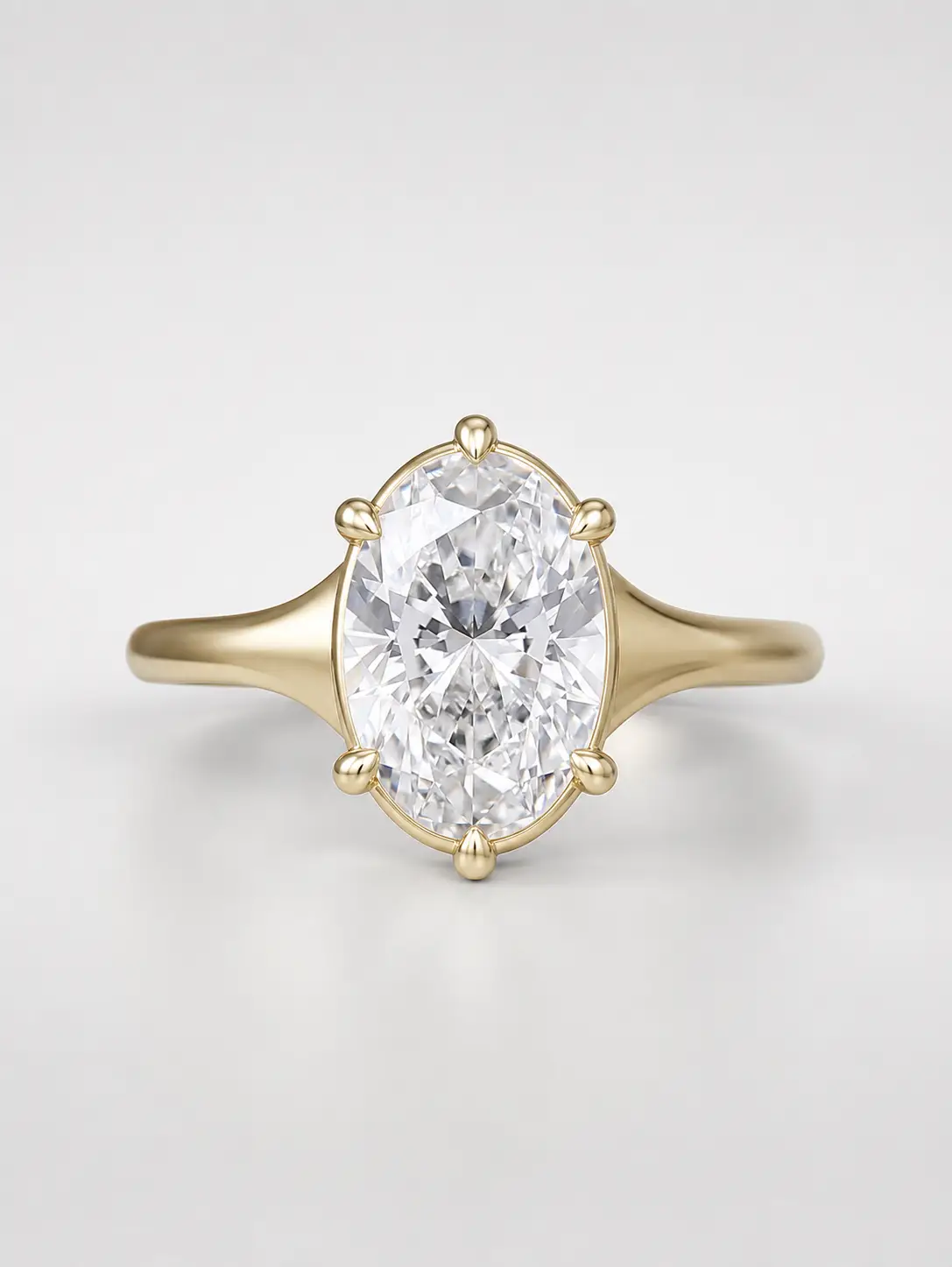 Oval cut diamond solitaire engagement ring on a tapered yellow gold band with a collet setting.