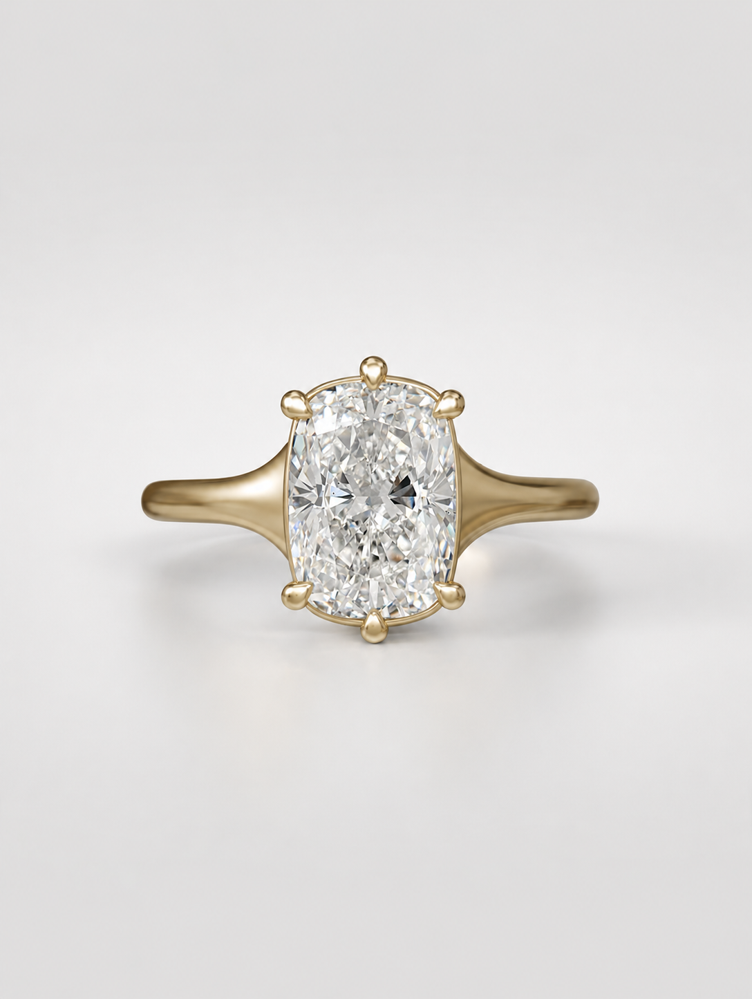 Elongated cushion cut diamond solitaire engagement ring on a tapered yellow gold band with a collet setting.