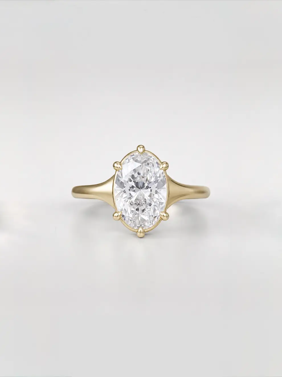 Oval cut diamond solitaire engagement ring on a tapered yellow gold band with a collet setting.