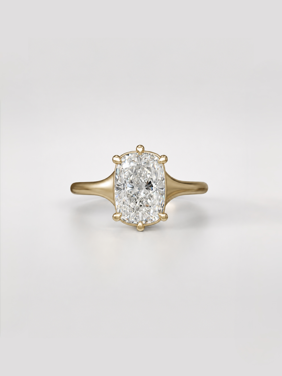 Elongated cushion cut diamond solitaire engagement ring on a tapered yellow gold band with a collet setting.